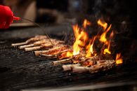 Close-up of meat grilling over an open flame, highlighting culinary techniques in Vancouver.