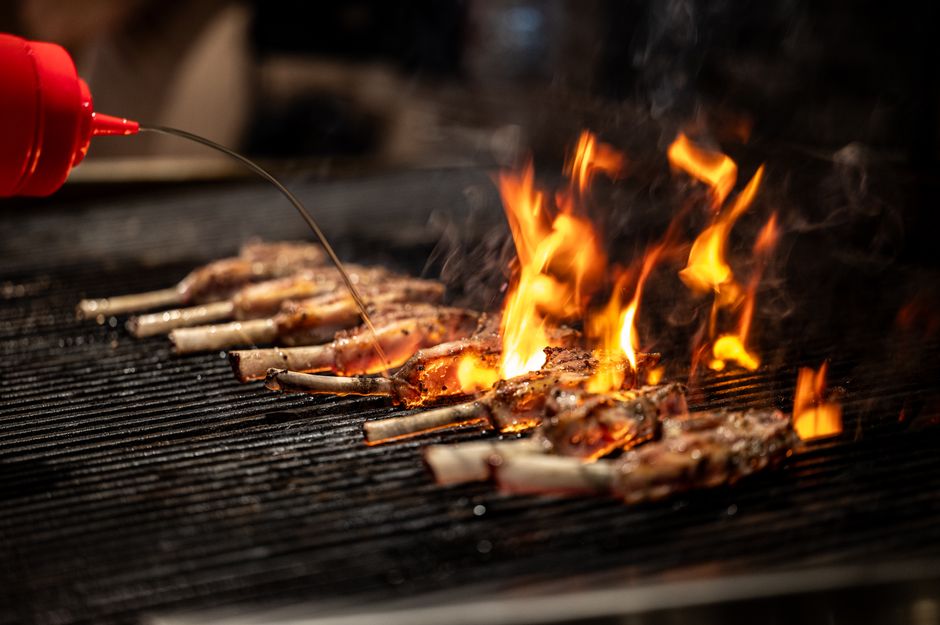 Close-up of meat grilling over an open flame, highlighting culinary techniques