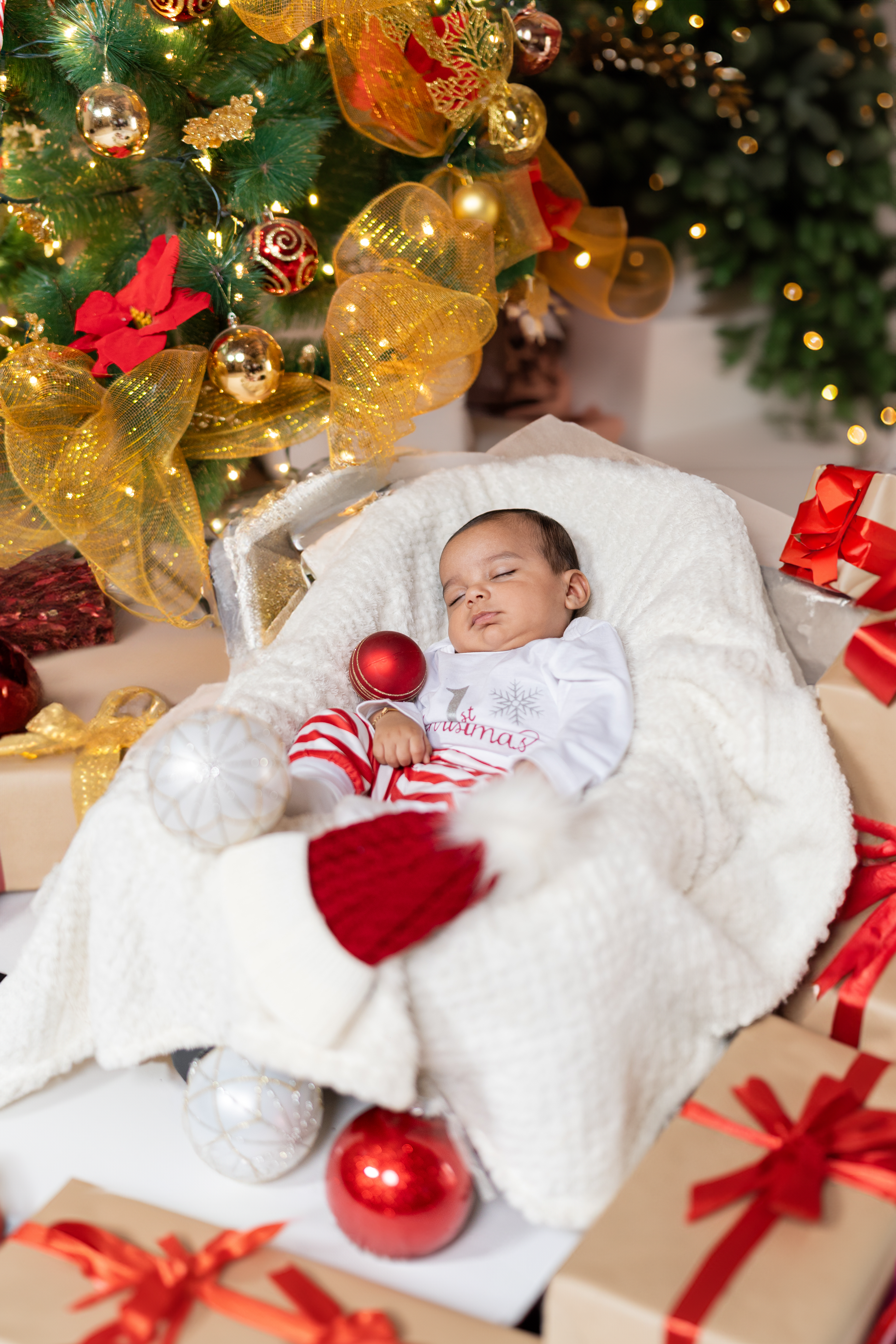 baby first Christmas photoshoot with twinkling holiday lights and festive decorations