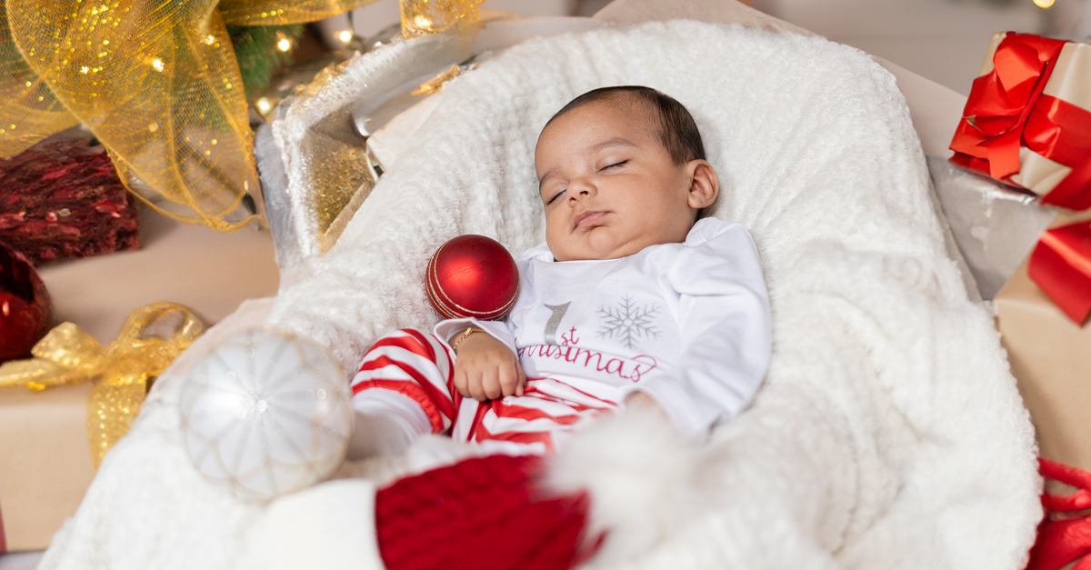 baby first Christmas photoshoot with twinkling holiday lights and festive decorations