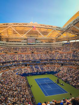 A vibrant tennis match in a large iconic stadium packed with engaged spectators.