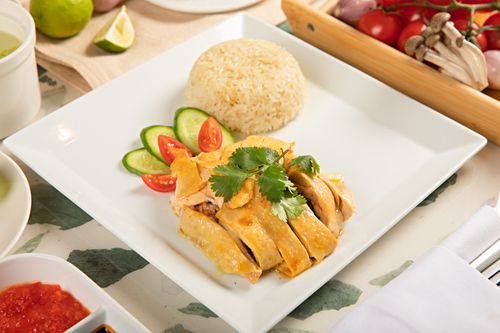 Free Delicious Hainanese chicken rice plated with fresh tomatoes and cucumbers. Stock Photo