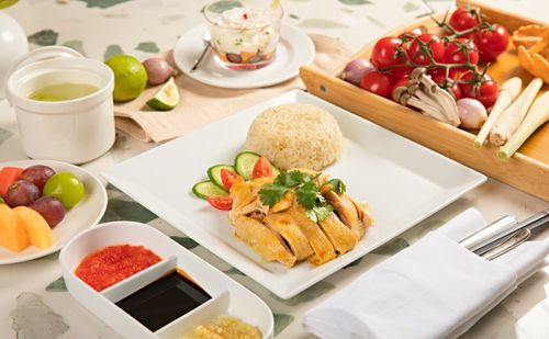 Free Tasty Hainanese chicken rice with fresh fruits and condiments, beautifully presented. Stock Photo