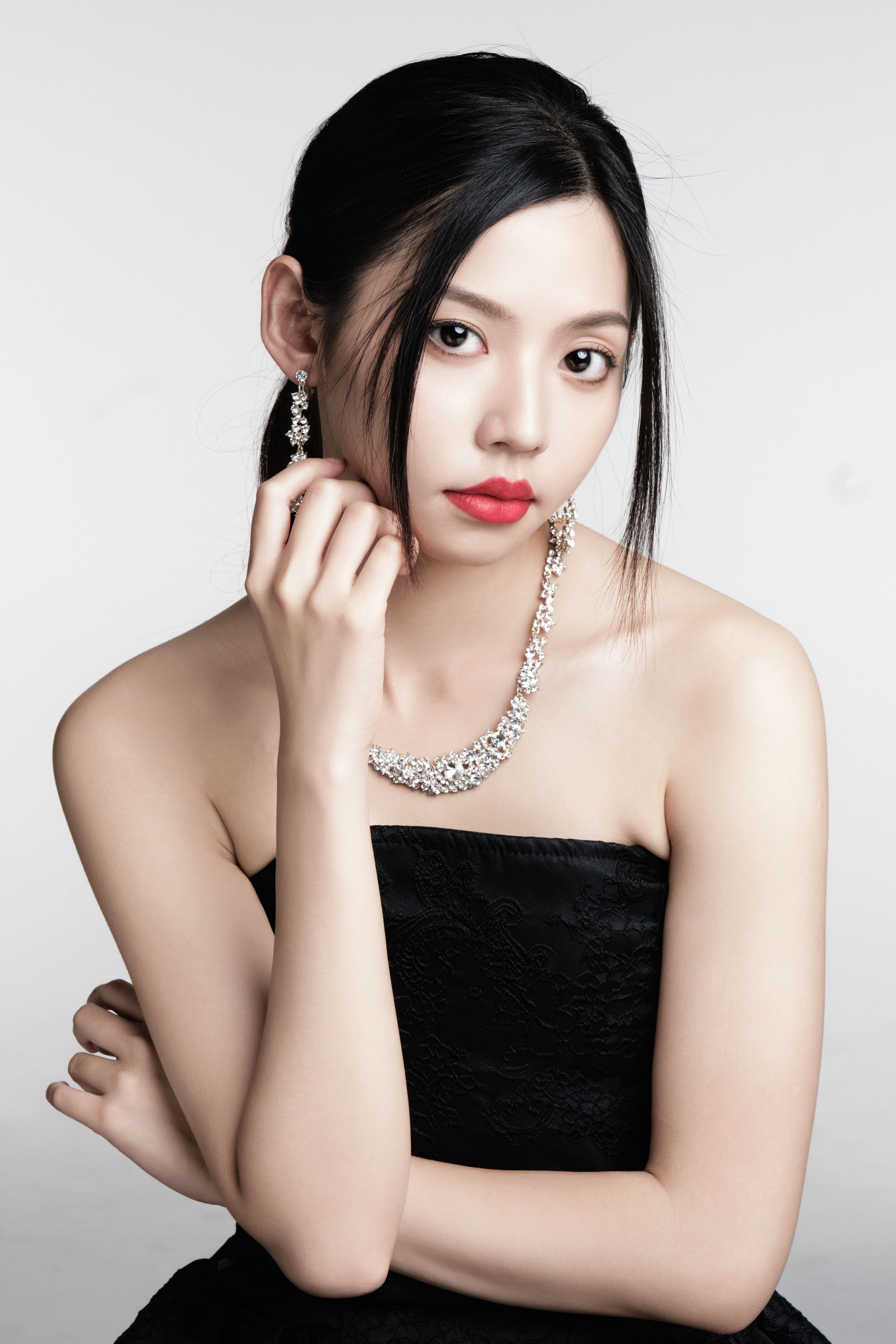 Sophisticated portrait of a young woman wearing elegant jewelry and a black dress.