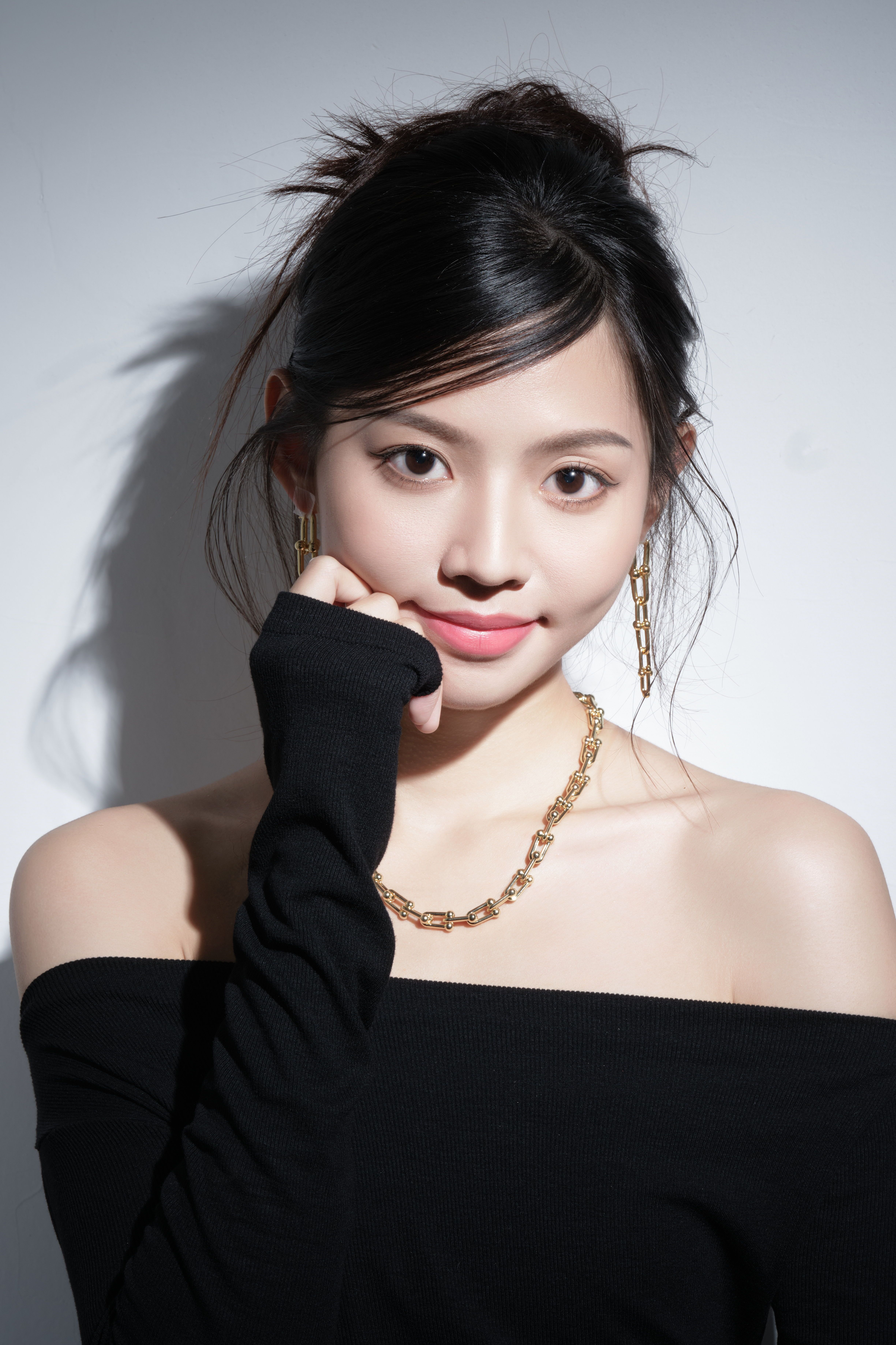 Stylish young woman in a chic black outfit with elegant jewelry, posing confidently.