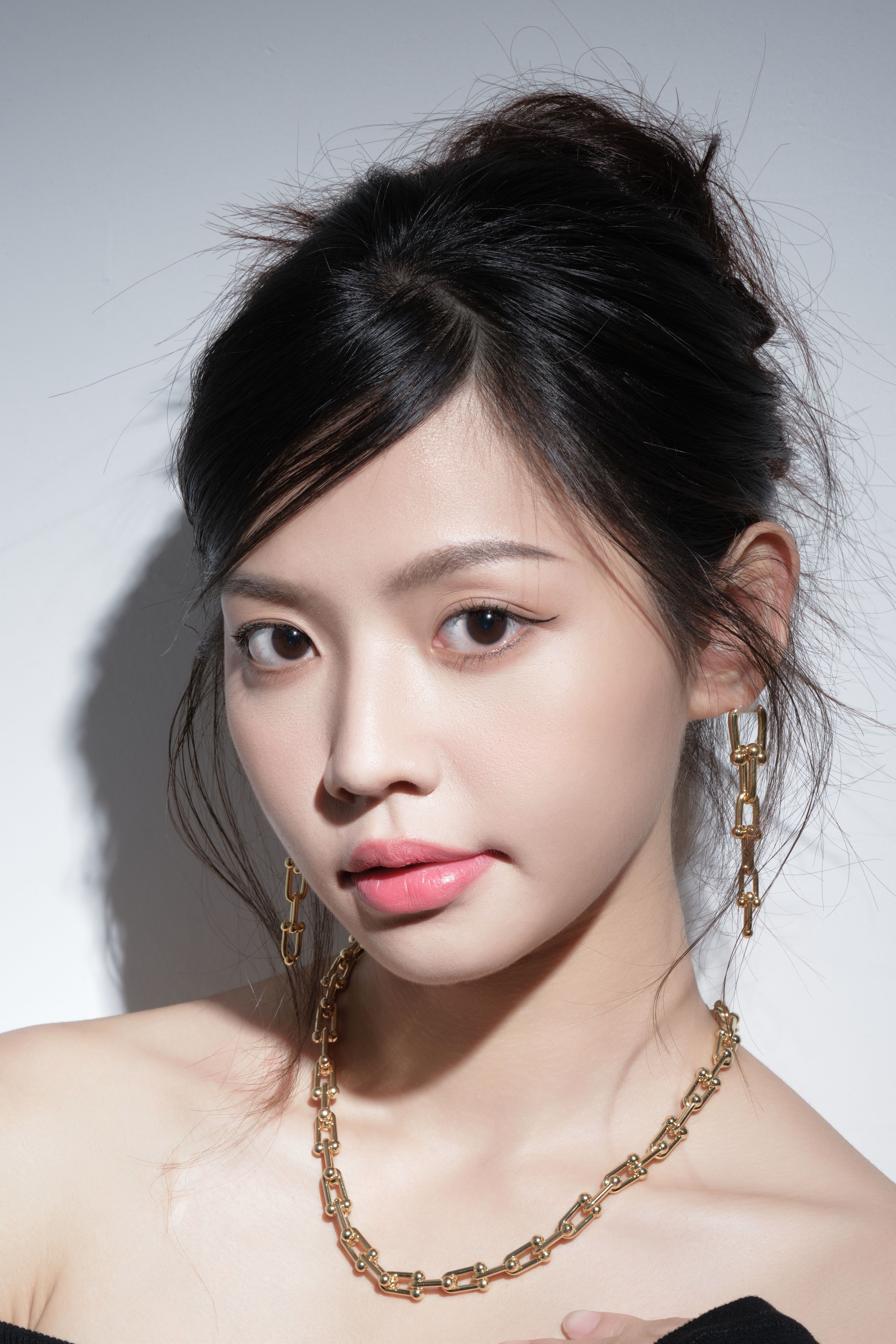 Stylish portrait of a woman wearing gold jewelry with soft lighting.