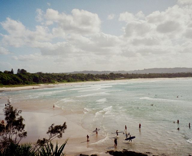 Explore the beautiful Byron Bay beach in NSW, Australia, with surfers enjoying the waves.