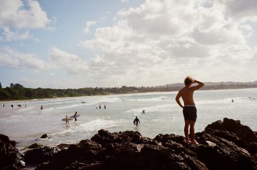 Free A surfer stands on rocks gazing at the surfing action in Byron Bay, Australia. Stock Photo