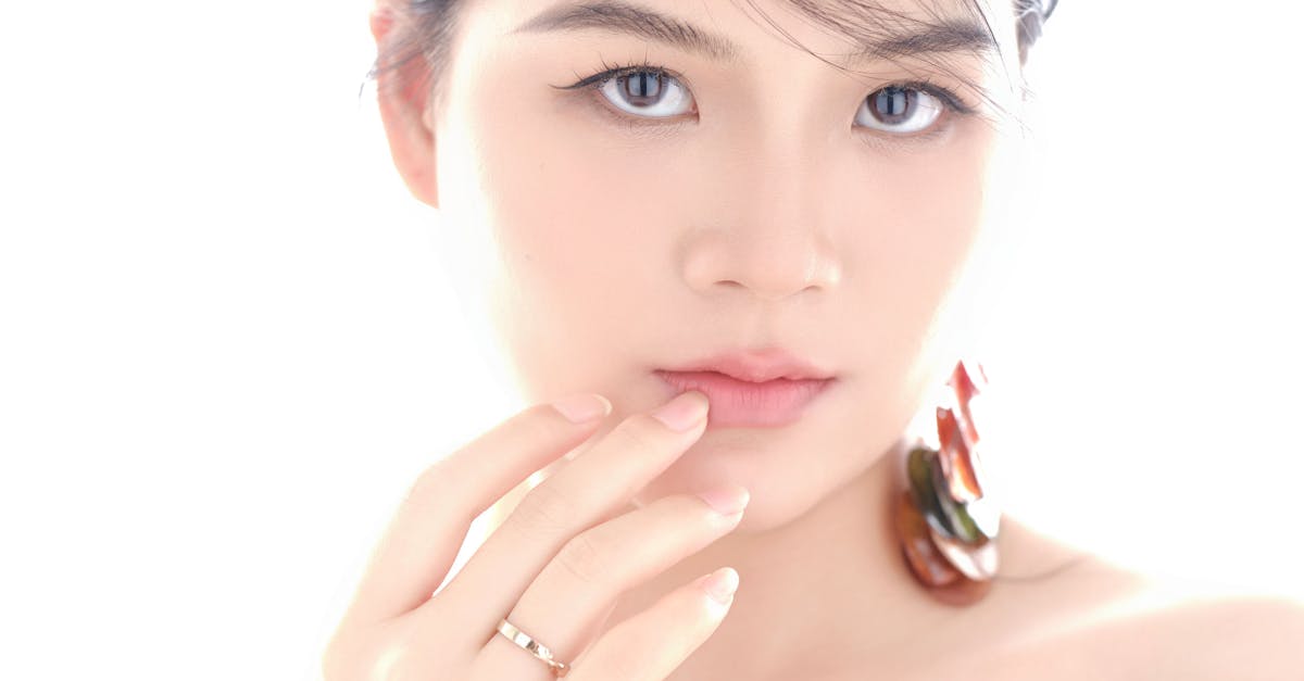A woman with perfect skin applying moisturizer to her face.