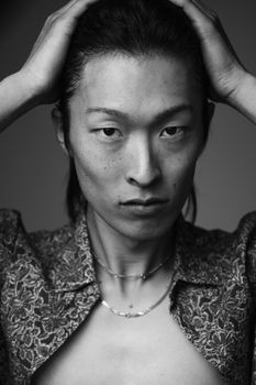 Black and white close-up portrait of a man with hands on head, displaying emotional intensity.