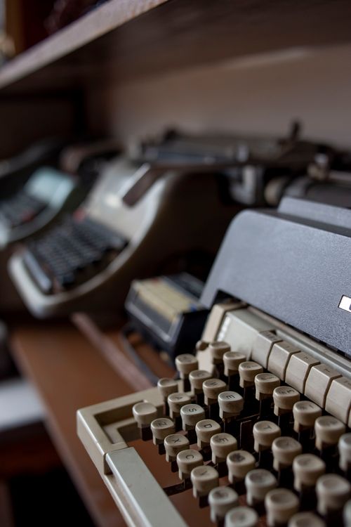 Free Close-up view of vintage typewriters arranged on a wooden shelf, showcasing a classic design. Stock Photo