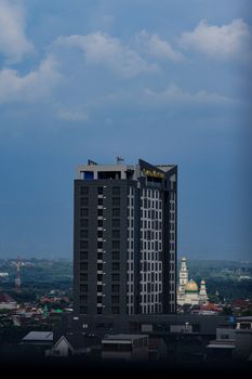 High-rise hotel building in Malang, Indonesia with cloudy sky background.