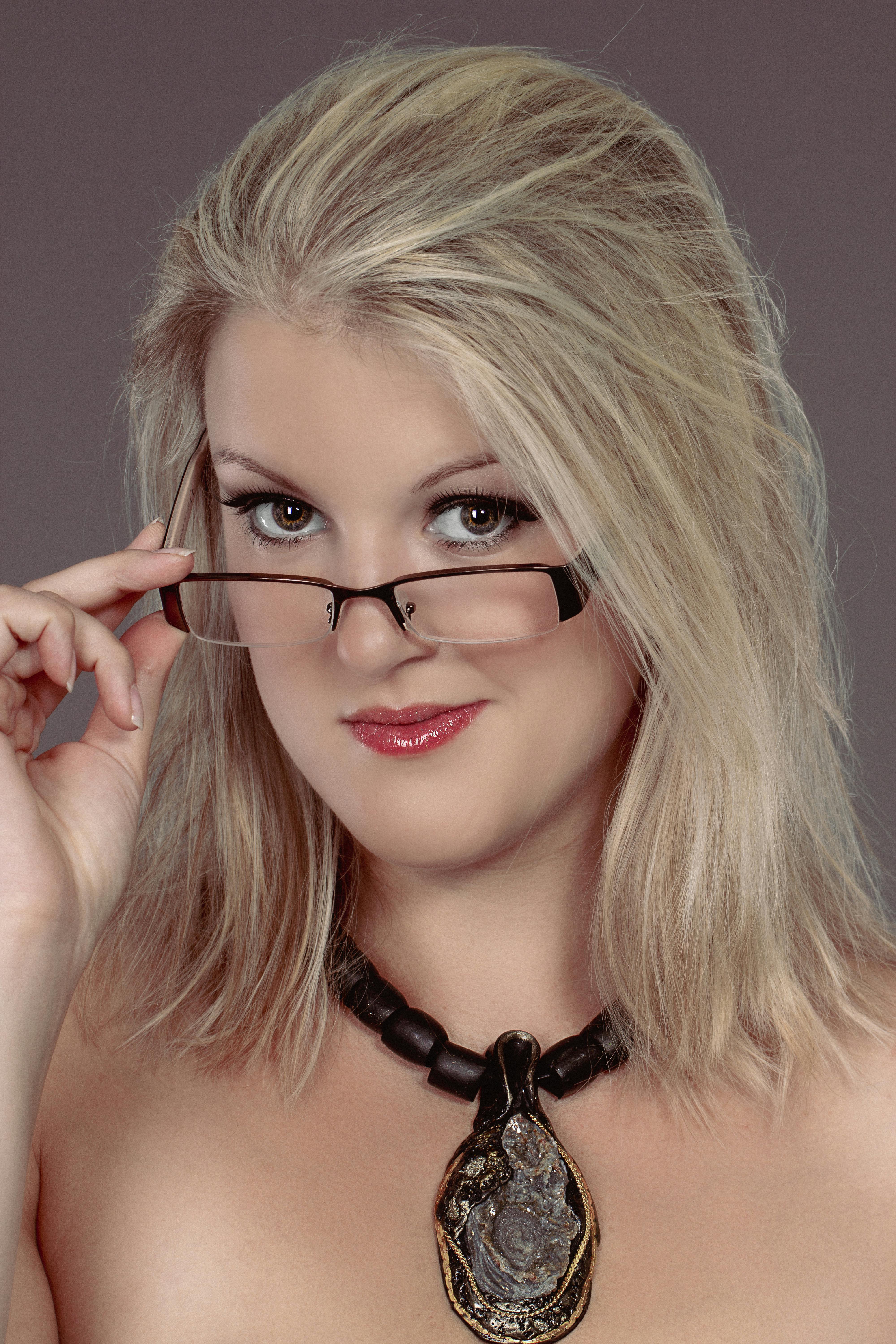 Portrait of a blonde woman wearing glasses and a statement necklace.