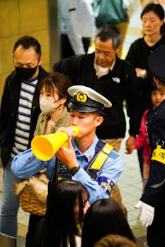 A Japanese police officer uses a megaphone for crowd control in a Tokyo subway station.