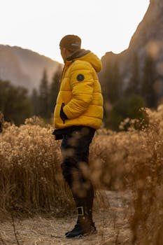 A person in a yellow jacket enjoys a scenic outdoor setting at sunset.
