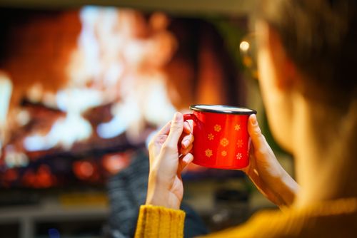 Free A relaxing winter evening with a warm drink by the fireplace. Perfect for cozy indoor moments. Stock Photo