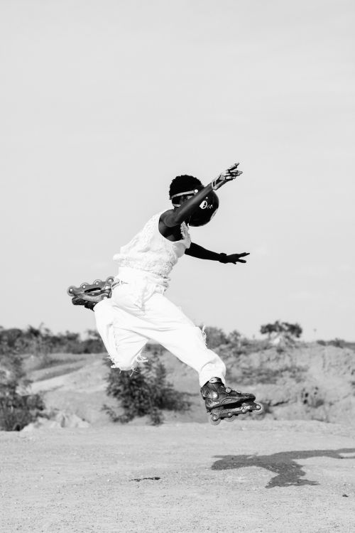 Free A person rollerblades mid-air in an expressive jump against an outdoor backdrop. Stock Photo