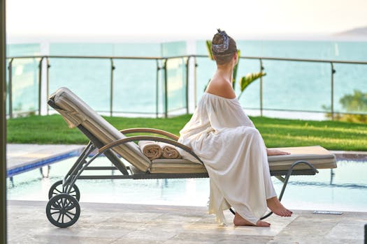 A woman in a white dress relaxes by the poolside with an ocean view.