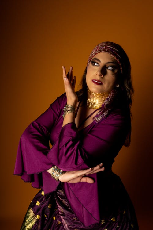 Free Graceful portrait of a female dancer in vibrant traditional attire, set against an orange backdrop. Stock Photo