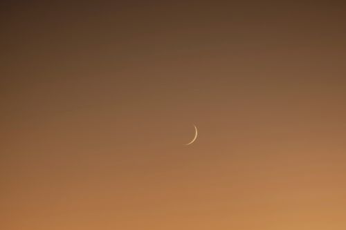 Free A delicate crescent moon graces the serene twilight sky with a warm golden hue. Stock Photo