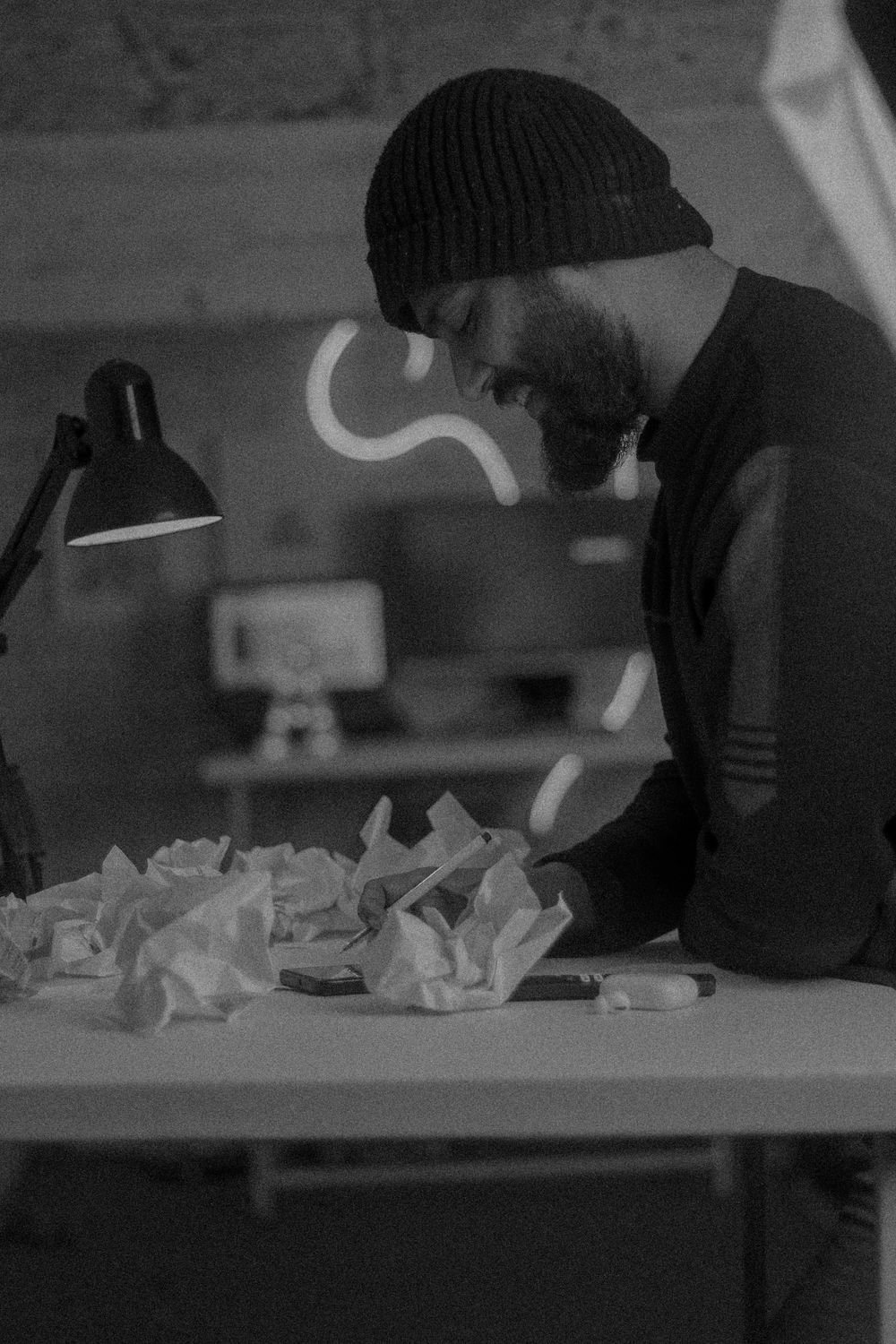 Contemplative Man Writing in Dimly Lit Workspace · Free Stock Photo