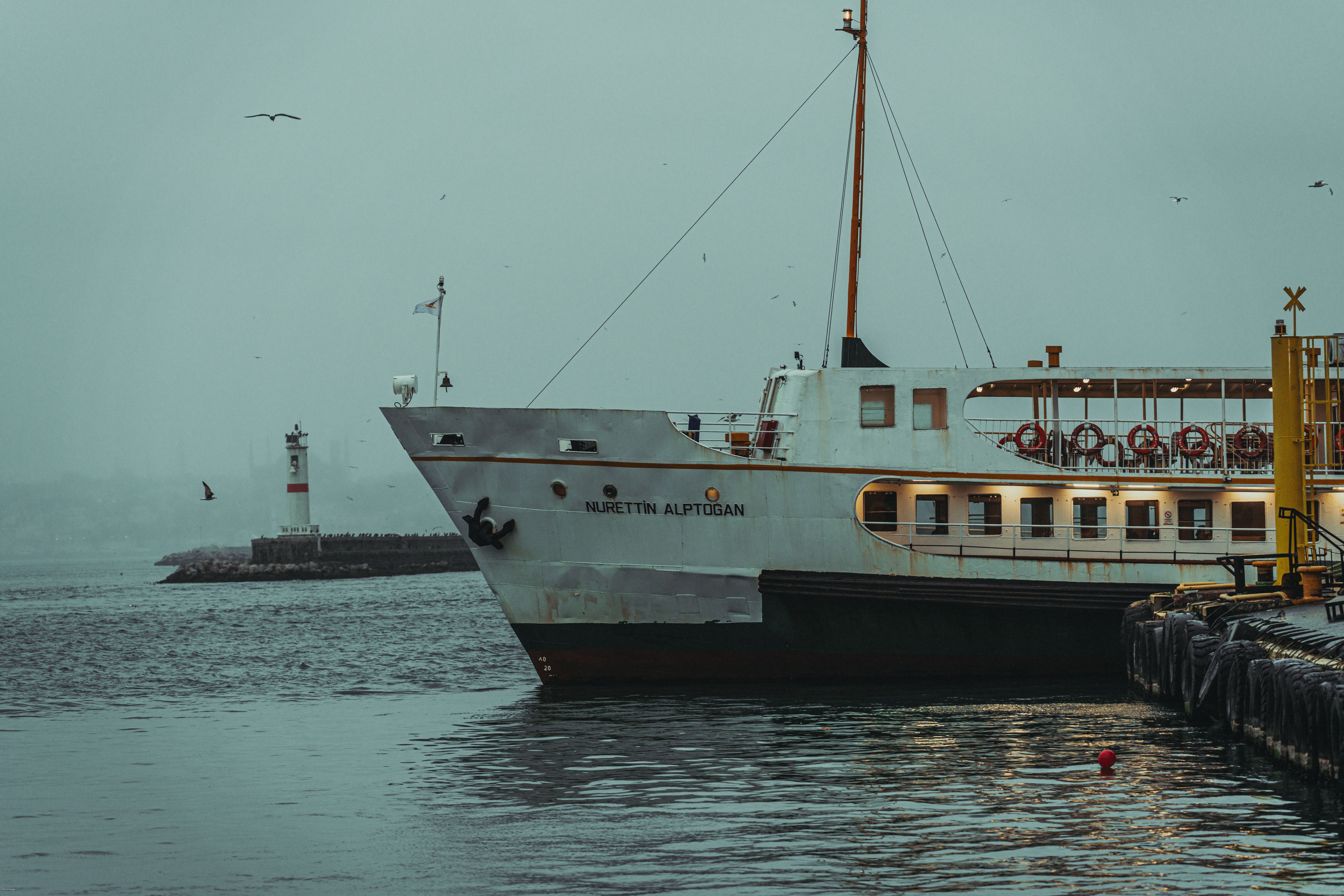 A ferry near a lighthouse in a foggy harbor