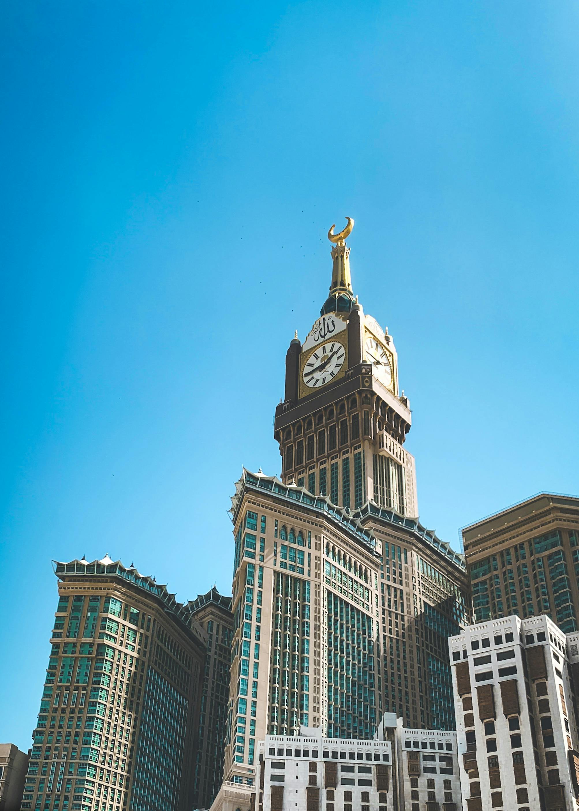 Tall Abraj Al Bait Towers in Mecca with clear blue sky. Iconic landmark showcasing Islamic architecture.