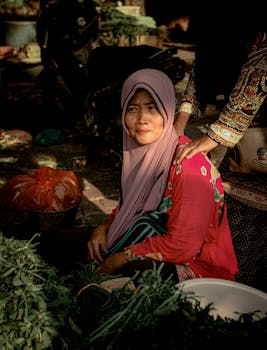 在印度尼西亚市场，身着传统服装的妇女出售新鲜蔬菜