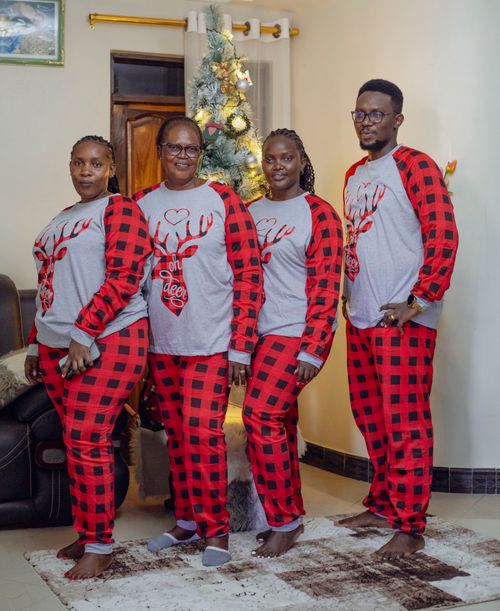 Free Family poses in matching Christmas pajamas by a tree, celebrating the holiday season. Stock Photo