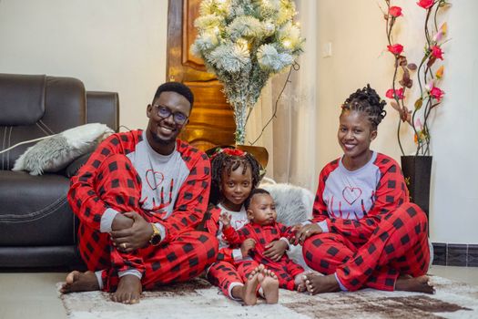 Happy family in matching plaid pajamas enjoying festive indoors setting with decor.