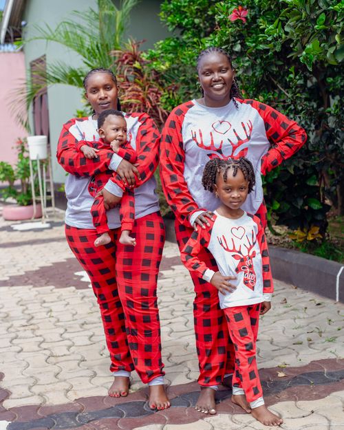 Free Smiling family wearing red plaid pajamas in the garden. Perfect family moment captured outdoors. Stock Photo