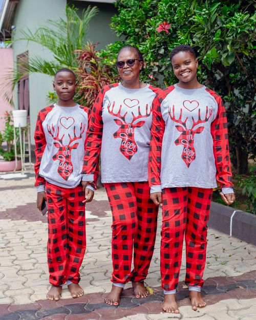 Free Family wearing matching Christmas pajamas with deer design, enjoying outdoor time together. Stock Photo