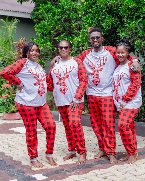 Free A joyful family wearing matching red plaid pajamas poses outdoors, embracing holiday spirit. Stock Photo