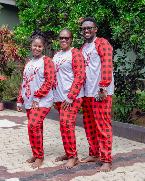 Free A joyful family poses in matching red and black plaid Christmas pajamas outdoors. Stock Photo