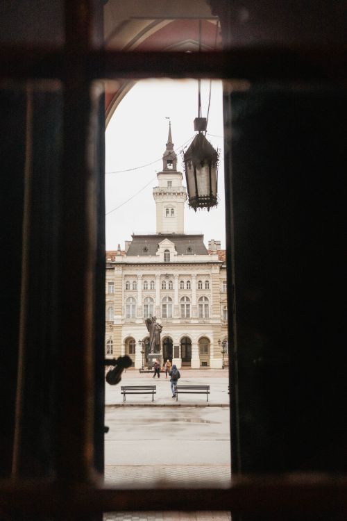 Free View of Novi Sad City Hall framed by an archway, demonstrating historical architecture in Serbia. Stock Photo