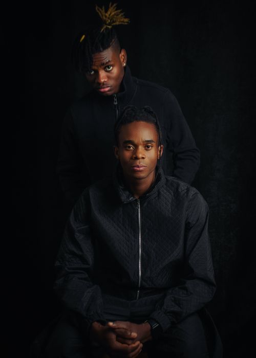 Free Artistic portrait of two men in dark attire against a dark background, exuding a strong mood. Stock Photo