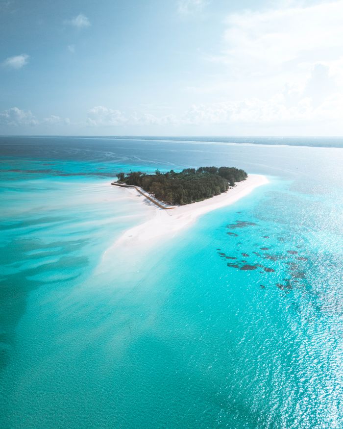 Aerial view of a tropical island surrounded by vibrant blue waters in Zanzibar