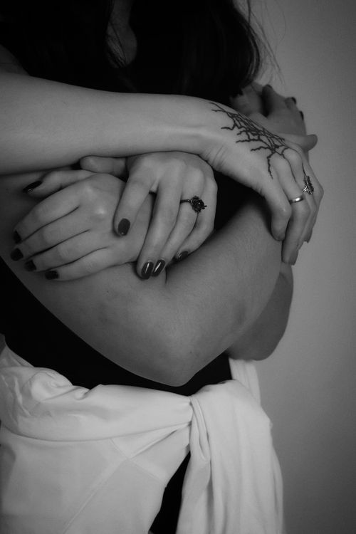 Free Close-up of a tender embrace showing hands with distinctive tattoos in black and white. Stock Photo