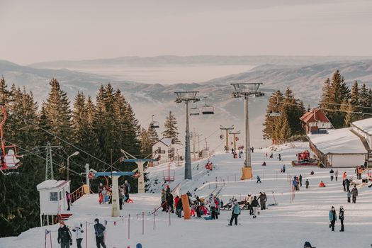 Winter activities at a ski resort in Romania's Parâng Mountains with snowy slopes.