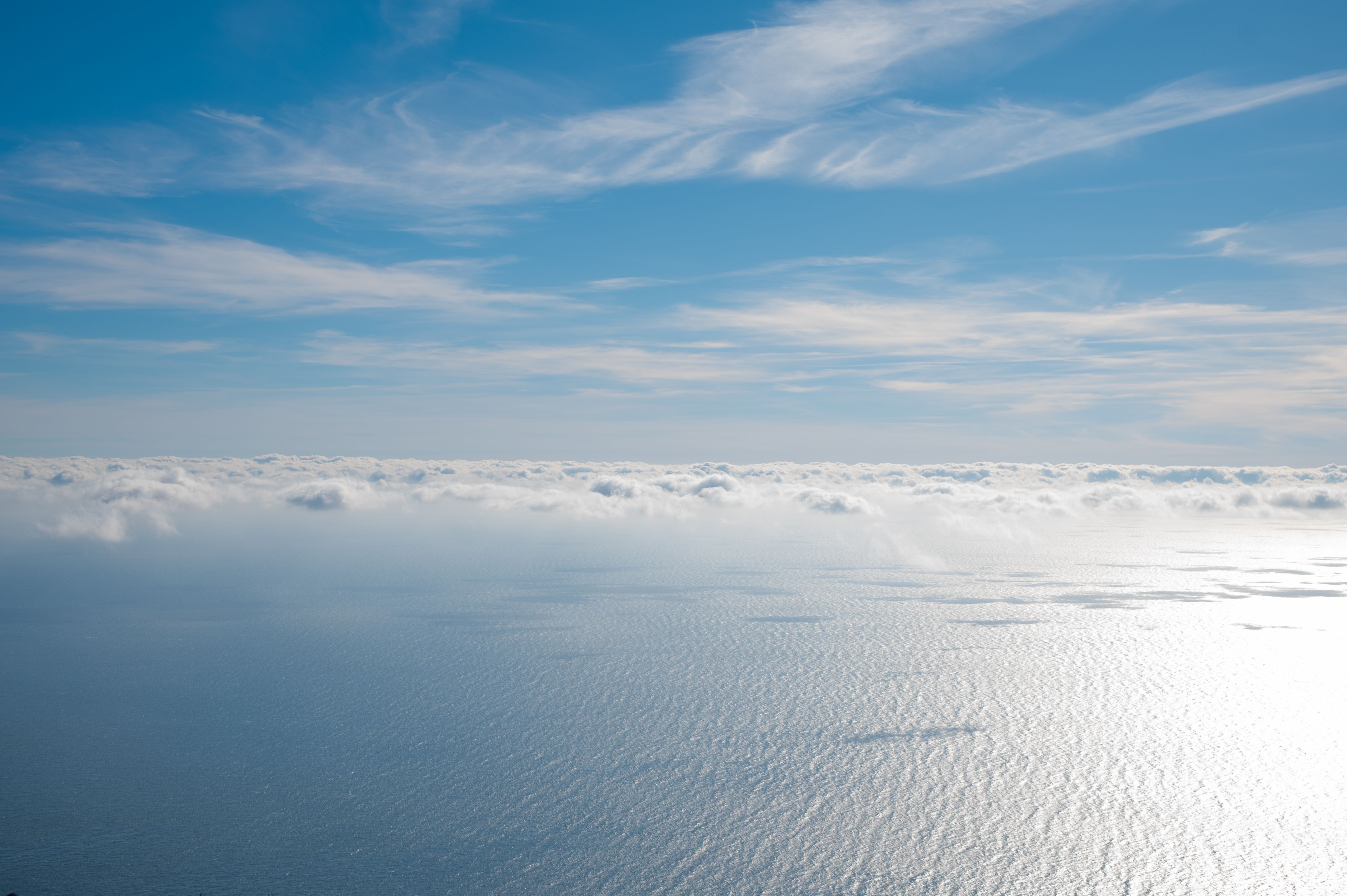 gratis Een rustgevende luchtfoto met donzige wolken boven een kalme oceaan onder een helderblauwe lucht. Stockfoto
