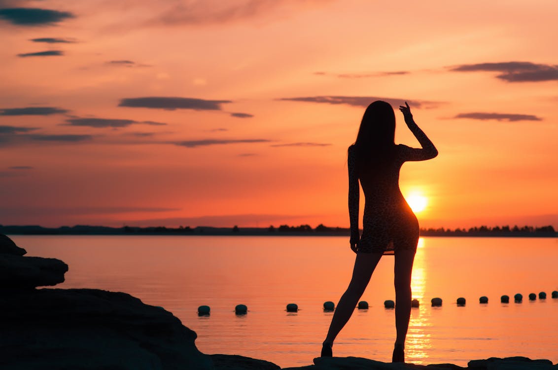 Free Silhouette of Woman Near Body of Water during Sunset Stock Photo