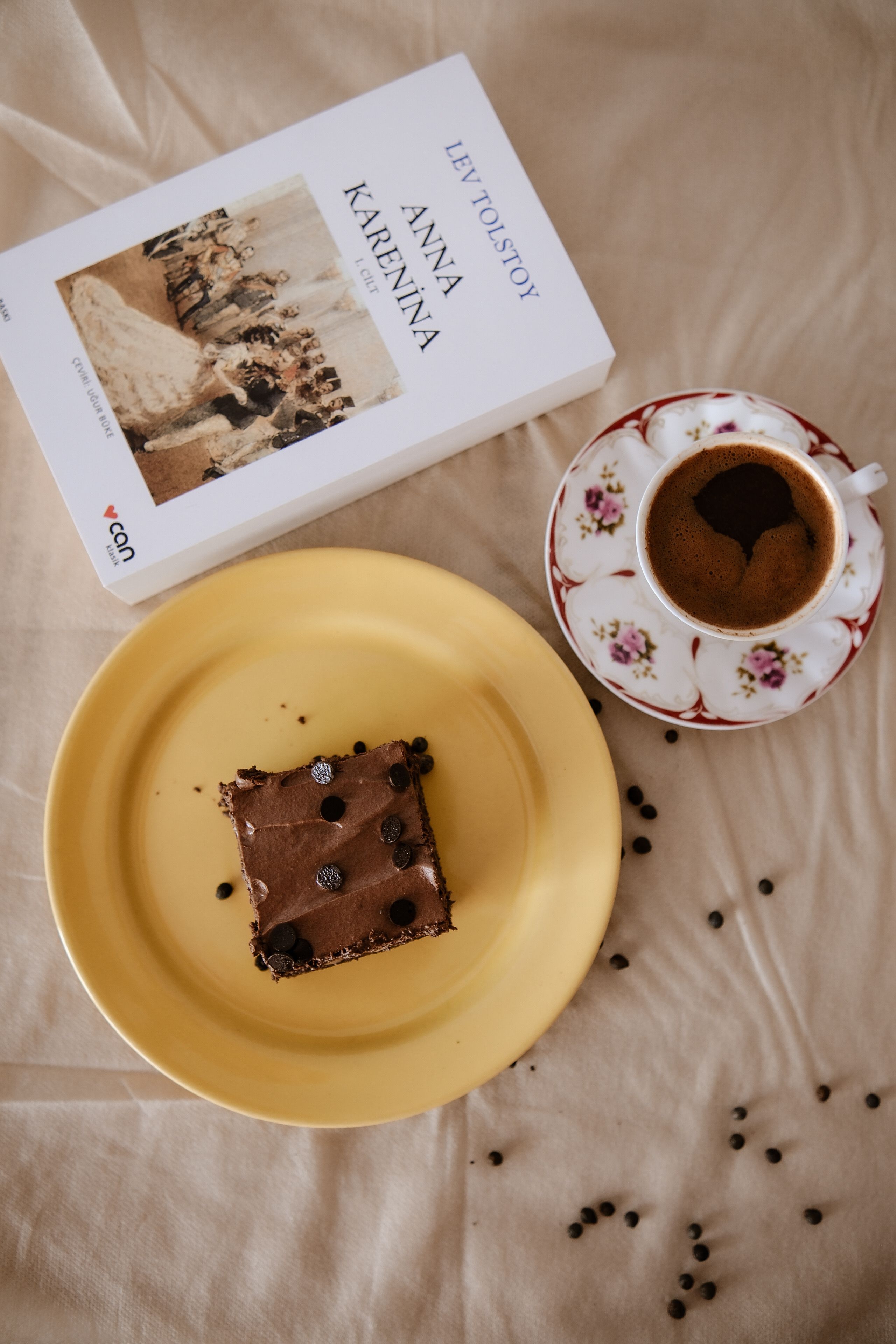 A serene setup with a book, coffee, and chocolate cake on a table.