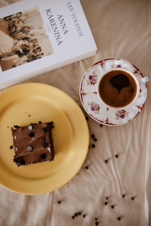 Free Top view of chocolate brownie, coffee, and Anna Karenina book on beige cloth. Stock Photo