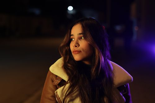 Free Portrait of a woman gazing into the distance under urban night lights. Stock Photo