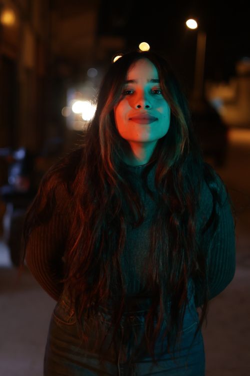 Free Portrait of a young woman with long hair under colorful night street lights. Stock Photo