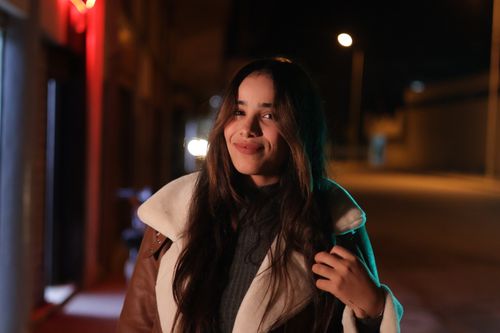 Free Night portrait of a woman with long hair smiling in an urban setting. Stock Photo