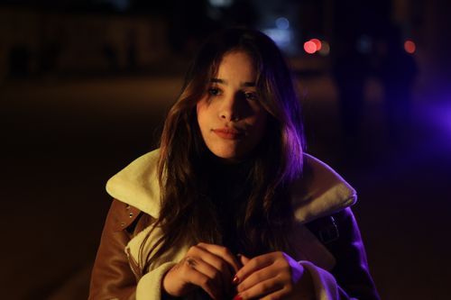Free Portrait of a young woman outdoors at night with dramatic lighting. Stock Photo