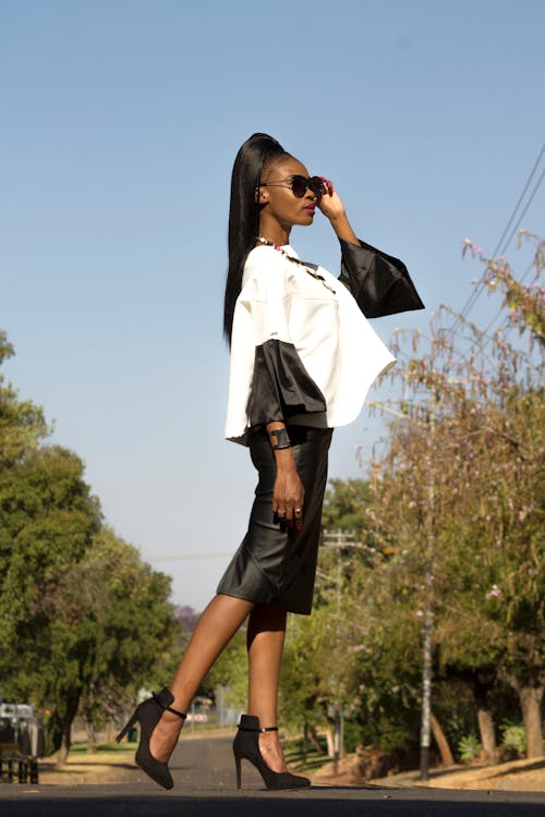 Side View Photo Stylish Woman in White and Black Long-sleeved Blouse and Black Dress Posing In the Middle of the Road