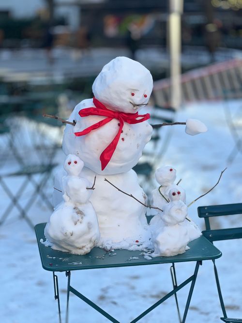 Free Cute snowman family with red scarf on a table in a snowy park setting. Stock Photo