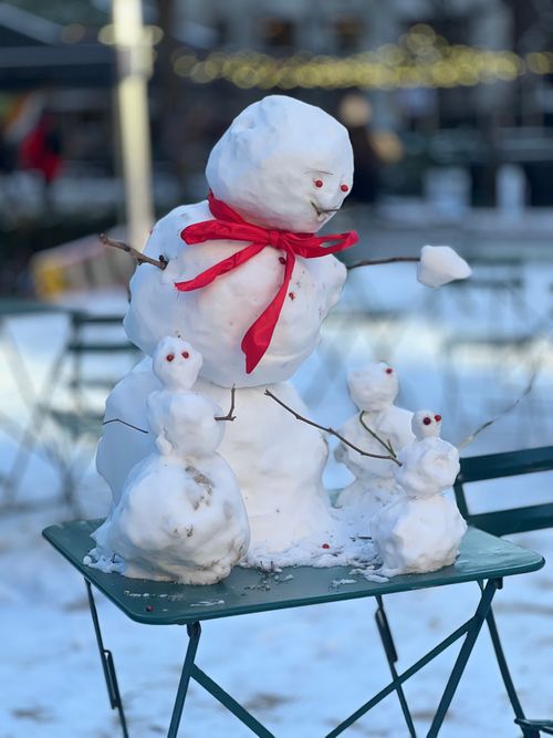 Free Whimsical snowman with red scarf surrounded by snow family on a winter day. Stock Photo